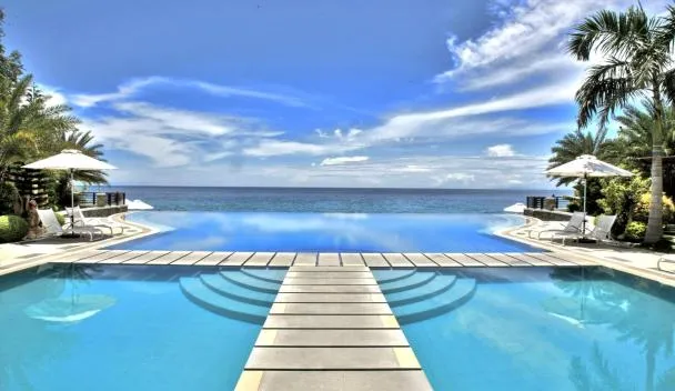 Acuatico Beach Resort infinity pool meeting the sea at Laiya Beach with palm trees