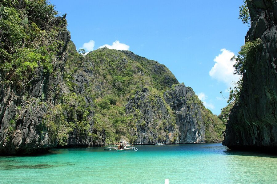 Big Lagoon at El Nido, with limestone cliffs framing turquoise water and a single bangka boat