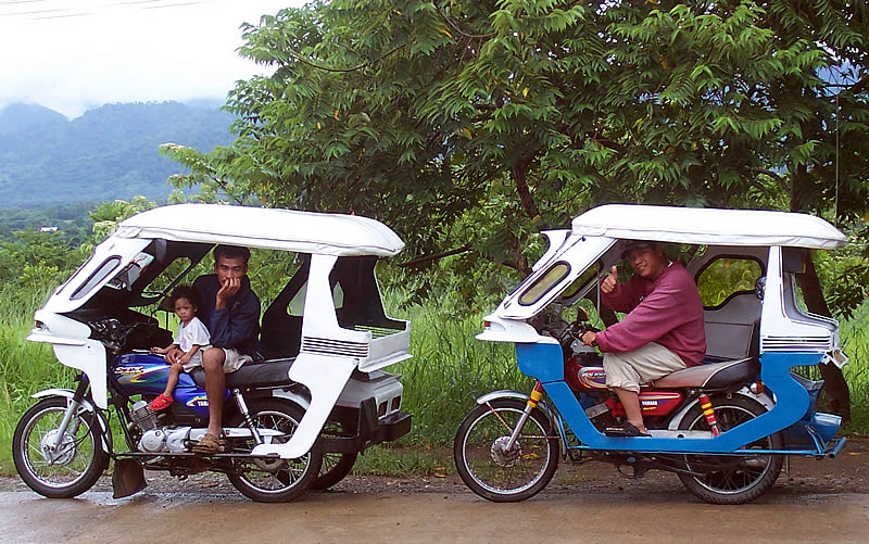 Two motorcycle tricycles parked on a road in Palawan, the standard local transport