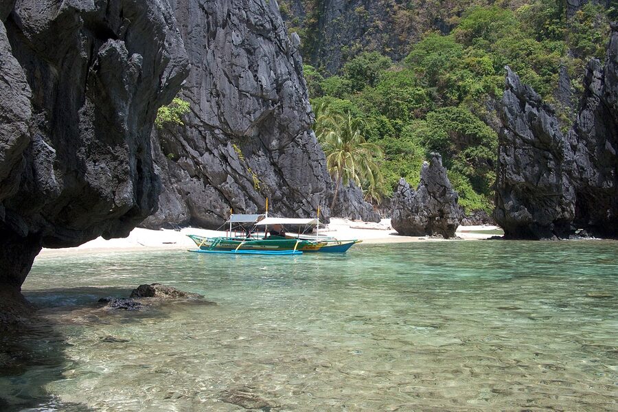 Tropical lagoon with limestone cliffs in Bacuit Bay, Palawan, with calm clear water and forested islets