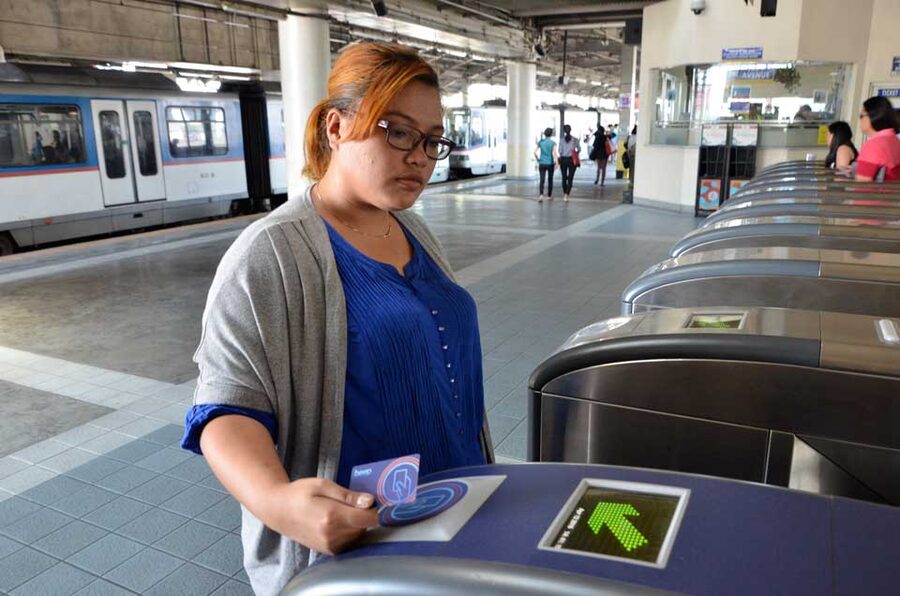 Passenger tapping a Beep card at a Manila train station gate