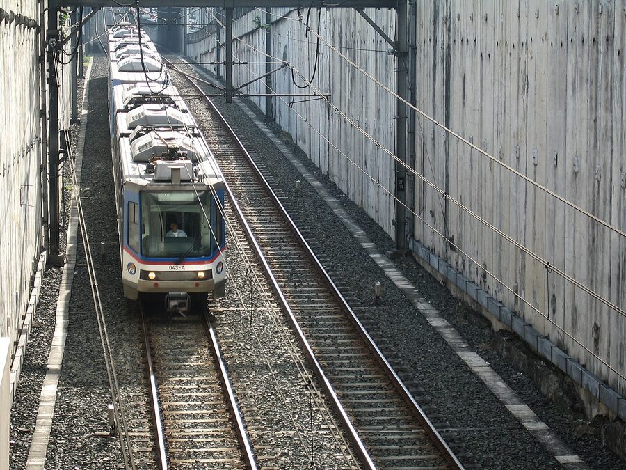 MRT-3 train pulling toward Ayala station between sound walls in Manila