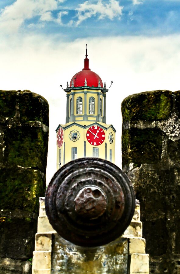 A view of the original Intramuros stone walls beside Manila City Hall, with restored brickwork and grassy moat ground