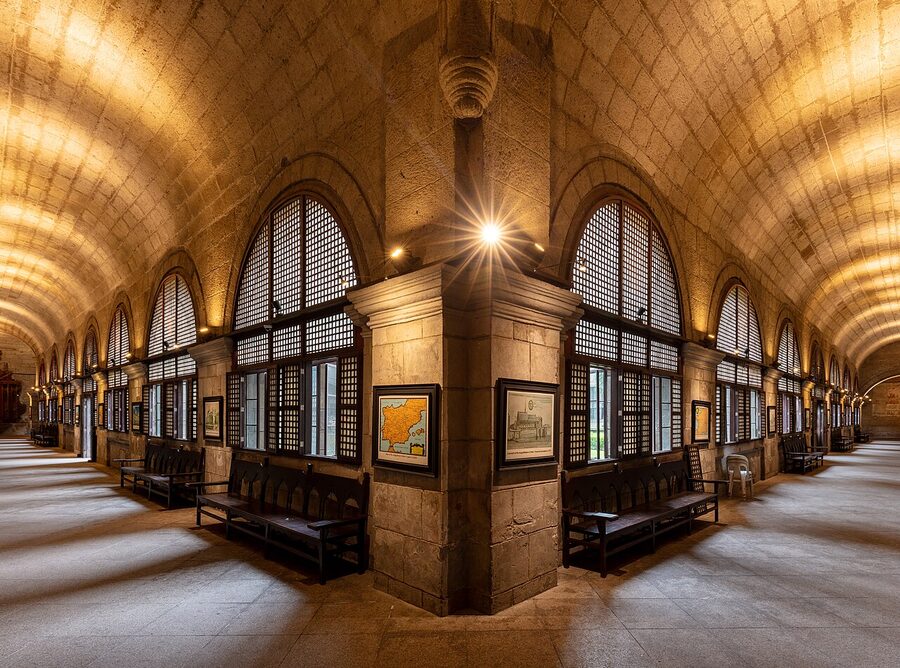 The vaulted cloister gallery of San Agustin Museum with arched windows, religious paintings, and stone benches