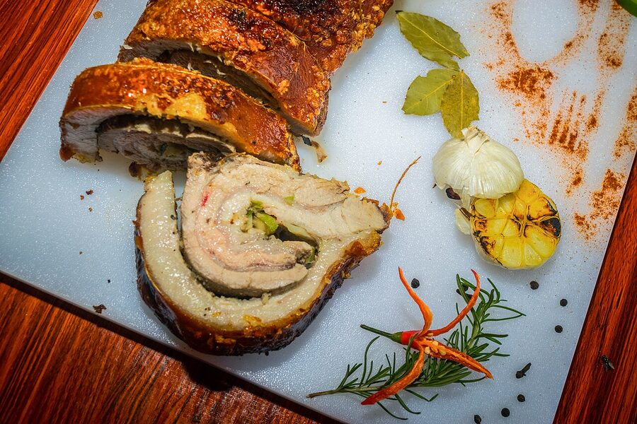 Sliced Pampanga style lechon belly stuffed and rolled on a wooden board