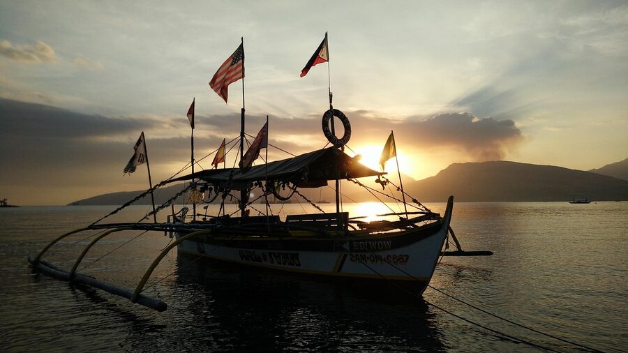 Sunset over Subic and Zambales coast with outrigger boat silhouette