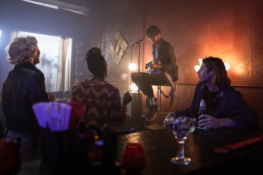 Musician playing guitar on a stool in a stylish bar setting