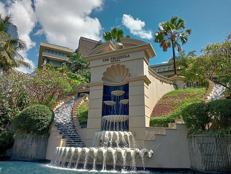 Peninsula Manila hotel exterior with shell-tier fountain and palm trees