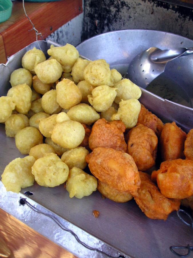 Filipino kwek-kwek battered quail eggs and fried fishballs piled together on a metal tray