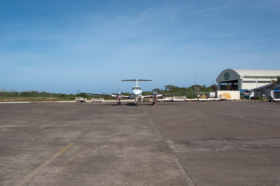 Small turboprop aircraft on the ramp at Puerto Princesa Airport with hangar in the background