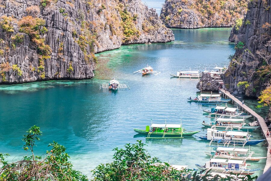 Coron Bay limestone karsts at golden hour with framing tropical foliage Palawan