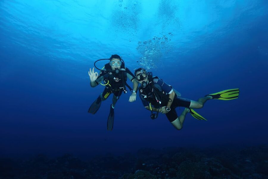 Two scuba divers descending into deep blue water