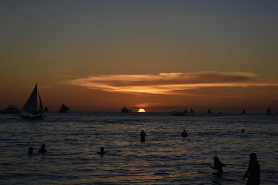 Boracay sunset with traditional sailboat silhouettes on White Beach Philippines