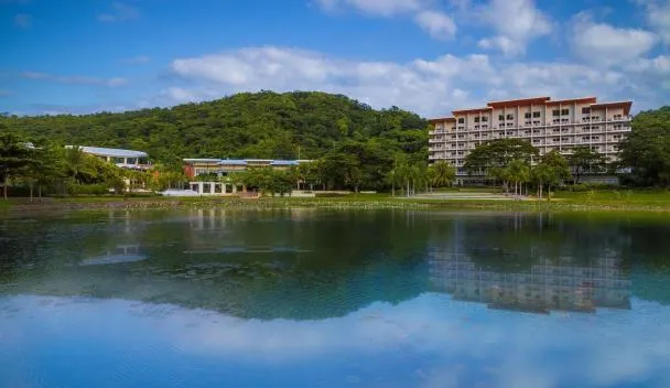 Pico Sands Hotel pool with palm trees and the hotel building behind it at Hamilo Coast