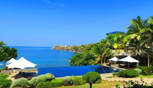 Punta Fuego cliffside infinity pool overlooking the bay with white tents and palm trees