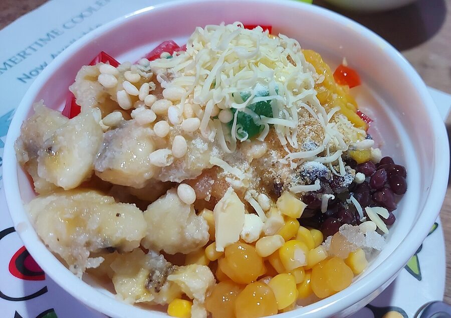 Halo-halo shaved ice dessert with red beans, sweet corn, banana, ube, leche flan and grated cheese