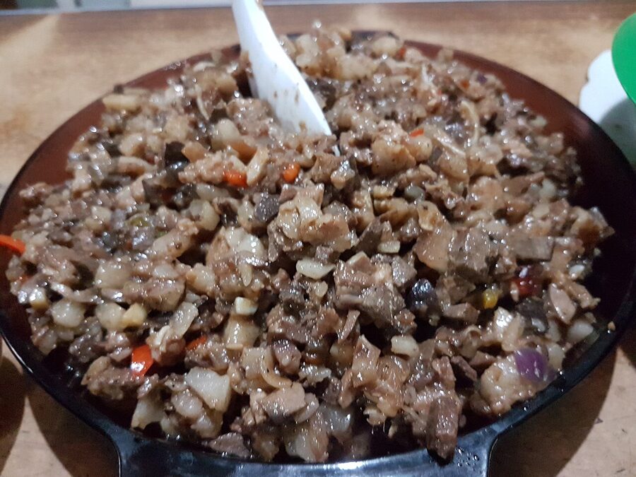 Sisig on a sizzling plate with onions, peppers and chillies, the chopped pork dish from Pampanga